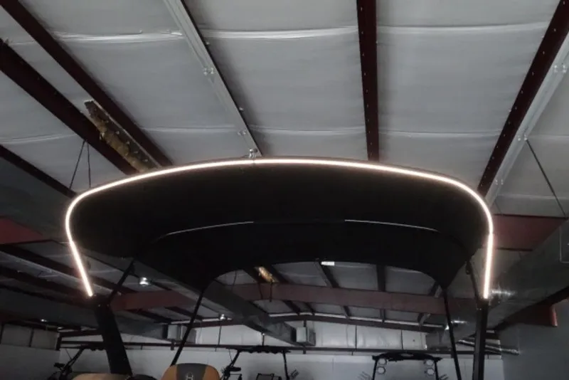 Slide: The Image of 2026 Harris Sunliner 250 boat canopy with LED lighting in a warehouse setting. - 19
