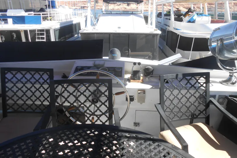 Slide: The Image of 1988 Lazy Days houseboat helm with decorative chairs and steering wheel, docked among other boats. - 29