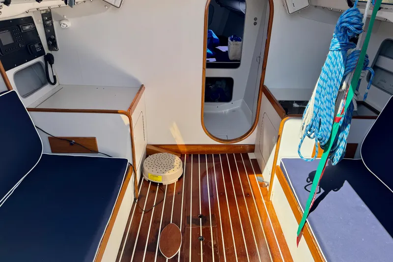 Slide: The Image of Interior of a 1999 J Boats J/105 sailboat with wood flooring and blue seating. - 14