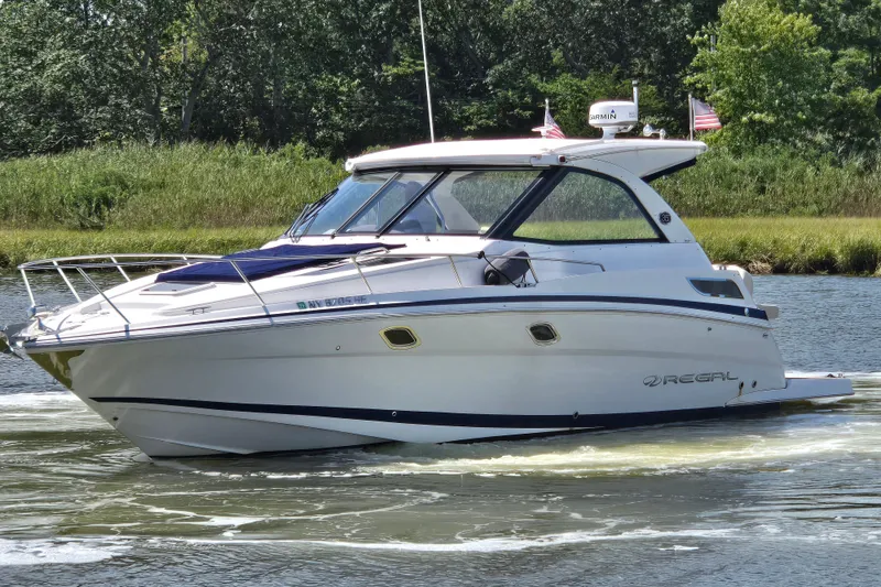 The Image of 2018 Regal 35 Sport Coupe cruising on a scenic waterway with lush greenery. - 0