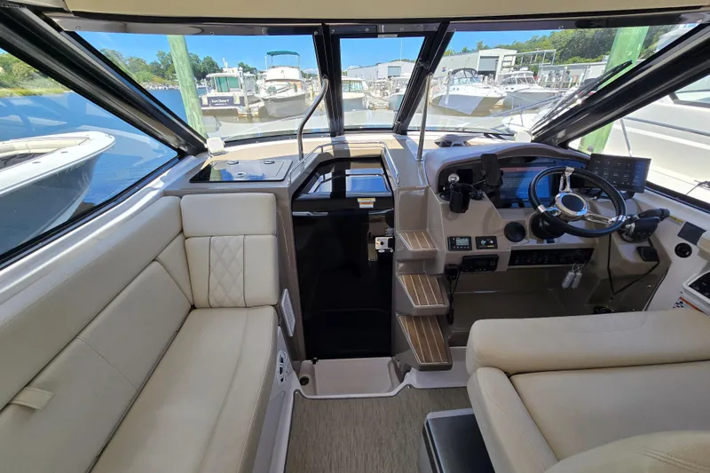Slide: The Image of 2018 Regal 35 Sport Coupe interior with helm, steering wheel, and beige seating at marina. - 11