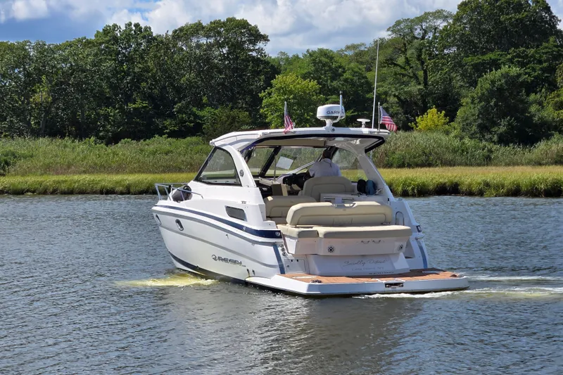 Slide: The Image of 2018 Regal 35 Sport Coupe cruising on a scenic river with lush greenery. - 6