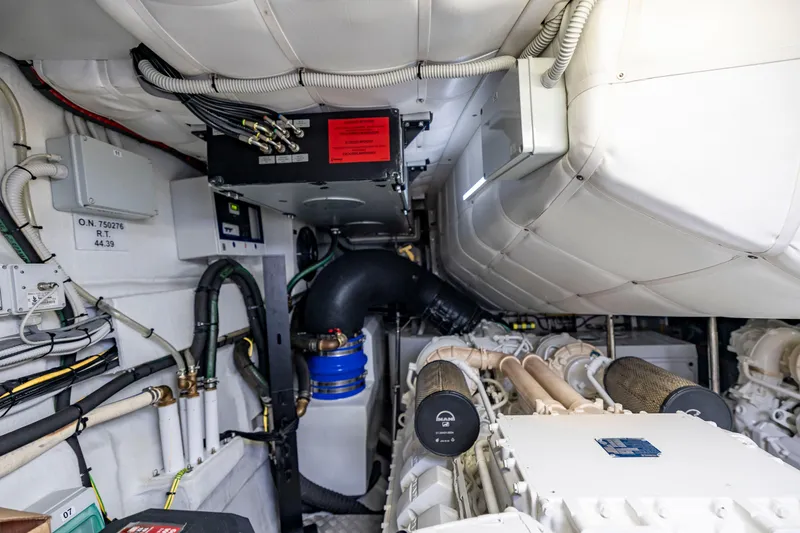 Slide: The Image of Engine room of a 2021 Pershing 62 yacht, showcasing mechanical components and wiring. - 125