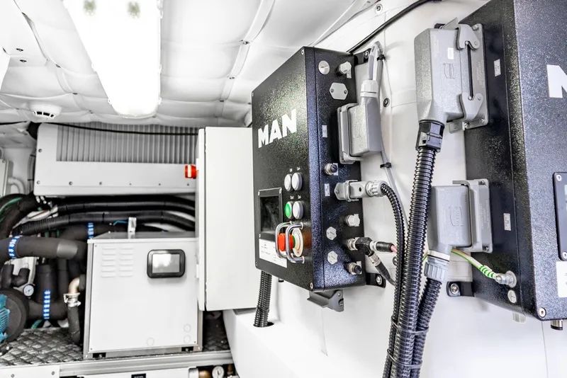 Slide: The Image of Engine room of 2021 Pershing 62 yacht, featuring MAN control panels and equipment. - 130