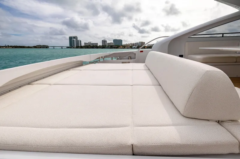 Slide: The Image of Luxurious sunbed on 2021 Pershing 62 yacht, overlooking serene ocean and city skyline. - 19