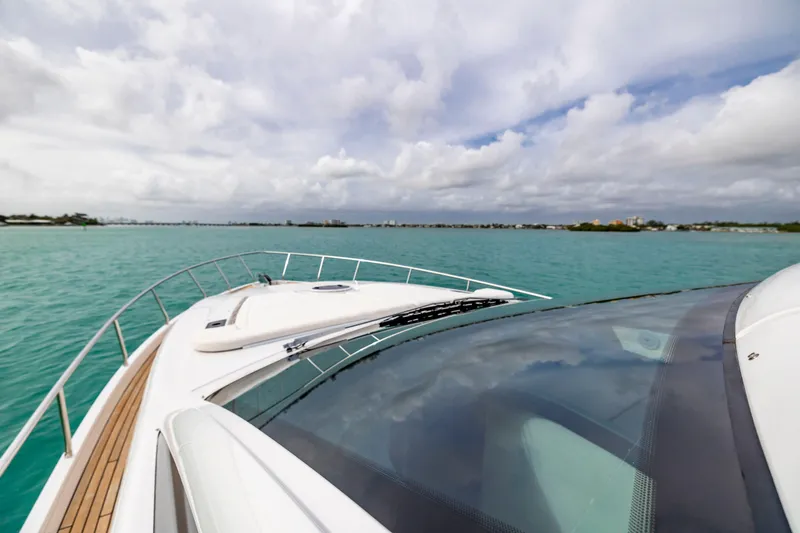 Slide: The Image of 2021 Pershing 62 yacht cruising on turquoise waters under a cloudy sky. - 23