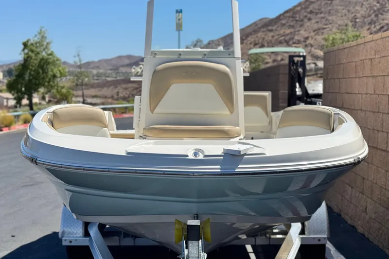 Slide: The Image of 2019 Stingray 206 CC boat on trailer, parked outdoors with scenic mountain backdrop. - 2