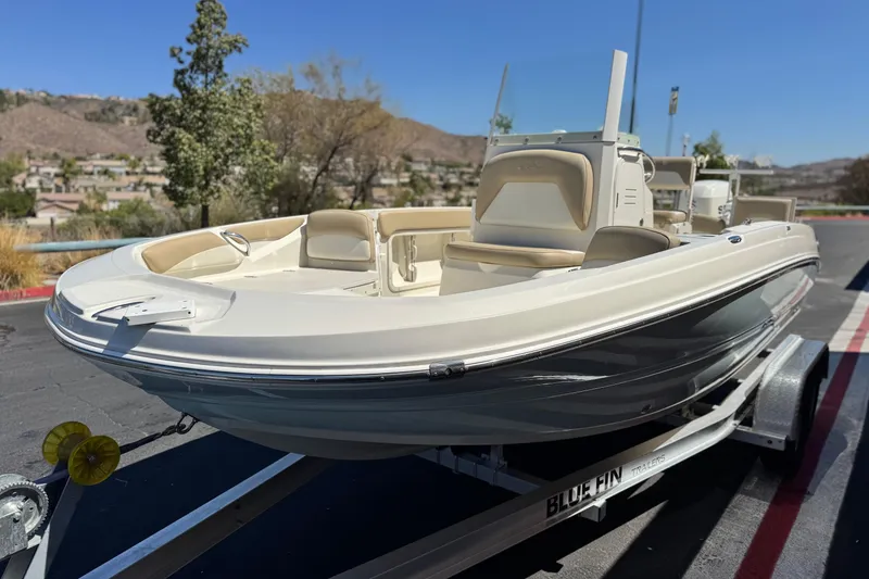 Slide: The Image of 2019 Stingray 206 CC boat on trailer, parked outdoors under clear blue sky. - 3