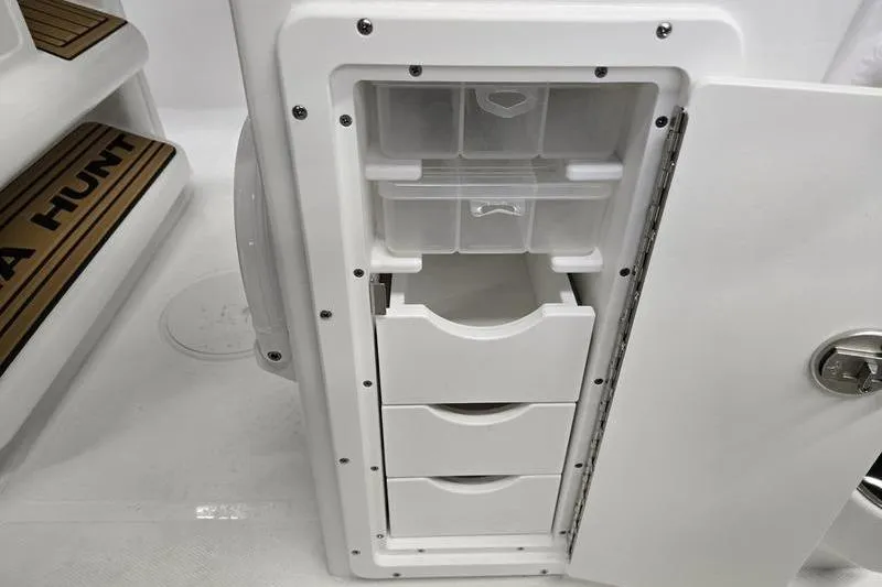 Slide: The Image of 2026 Sea Hunt Ultra 245 SE boat storage compartment with open drawers and organizer. - 15