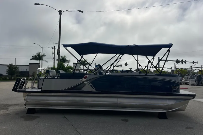 Slide: The Image of 2026 Avalon 2385 LSZ Quad Lounger Tri Toon boat with canopy, parked outdoors. - 4