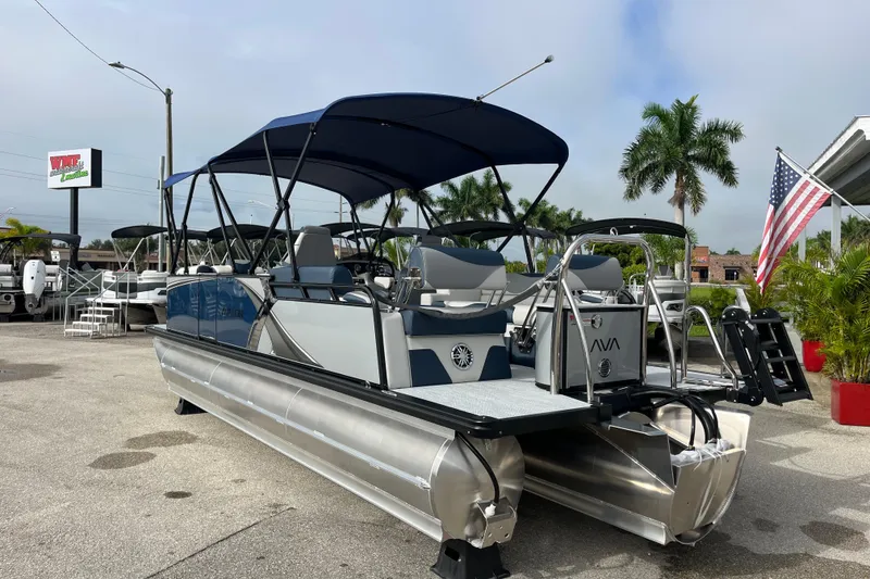 Slide: The Image of 2026 Avalon 2385 LSZ Quad Lounger Tri Toon boat displayed outdoors with American flag. - 7
