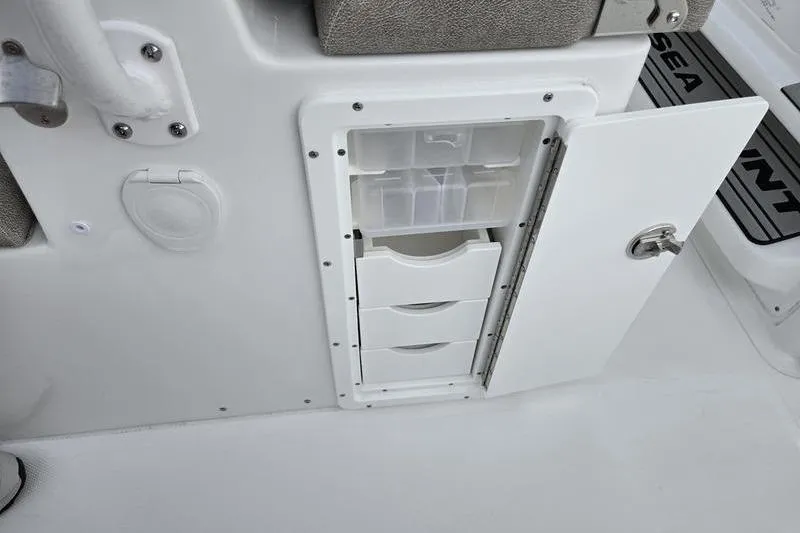 Slide: The Image of Storage compartment on 2026 Sea Hunt Ultra 275 SE boat with open door and drawers. - 11