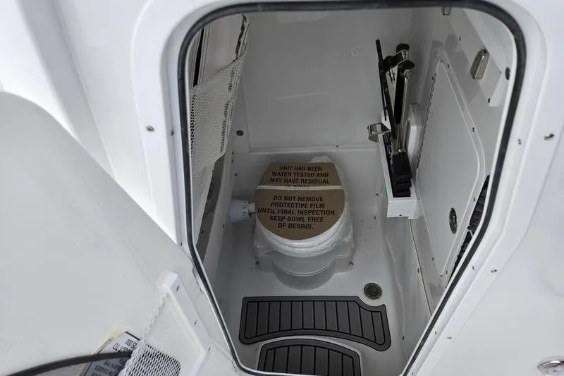 Slide: The Image of Interior of 2026 Sea Hunt Ultra 275 SE boat, featuring a compact marine toilet. - 18