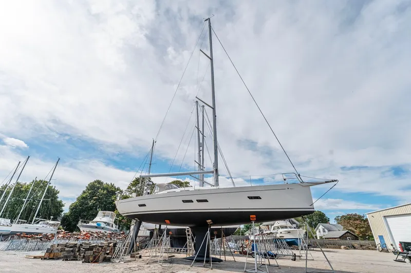Slide: The Image of Italia Yachts 13.98 sailboat from 2015 on dry dock under a cloudy sky. - 2