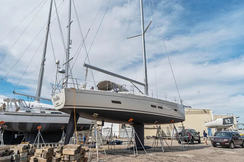 Slide: The Image of 2015 Italia Yachts 13.98 sailboat on dry dock, surrounded by other boats and vehicles. - 7