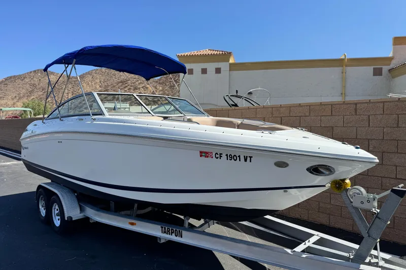 Slide: The Image of 2008 Cobalt 262 boat on trailer with blue canopy, parked near brick wall. - 1