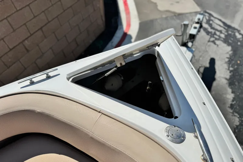 Slide: The Image of 2008 Cobalt 262 boat bow with open storage compartment, beige seating, and metal fittings. - 15