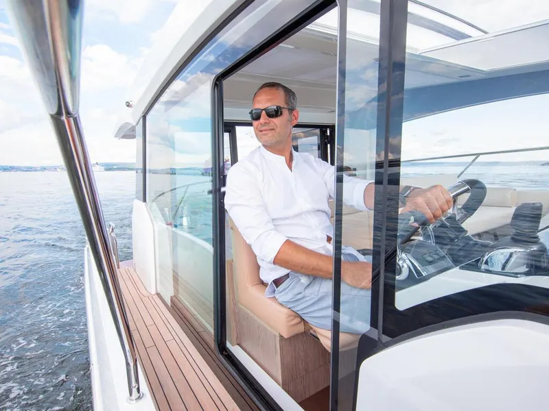 Slide: The Image of Man piloting 2026 Sealine C390 yacht on open water, wearing sunglasses and white shirt. - 20