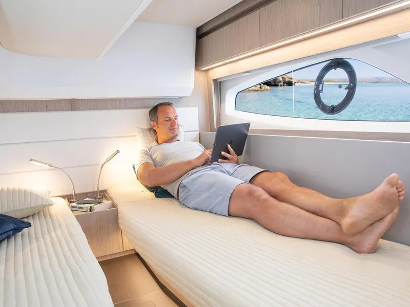 Slide: The Image of Man relaxing on a 2026 Sealine C390 yacht, using a tablet in a cozy cabin. - 30