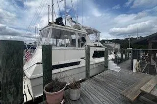 Slide: The Image of 1990 Hatteras 40 Motor Yacht docked at a marina under a cloudy sky. - 4