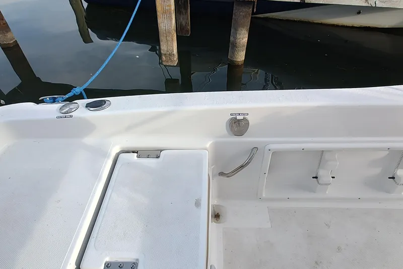 Slide: The Image of NauticStar 231 Hybrid boat deck, featuring storage compartments and fresh water access, docked by wooden posts. - 10