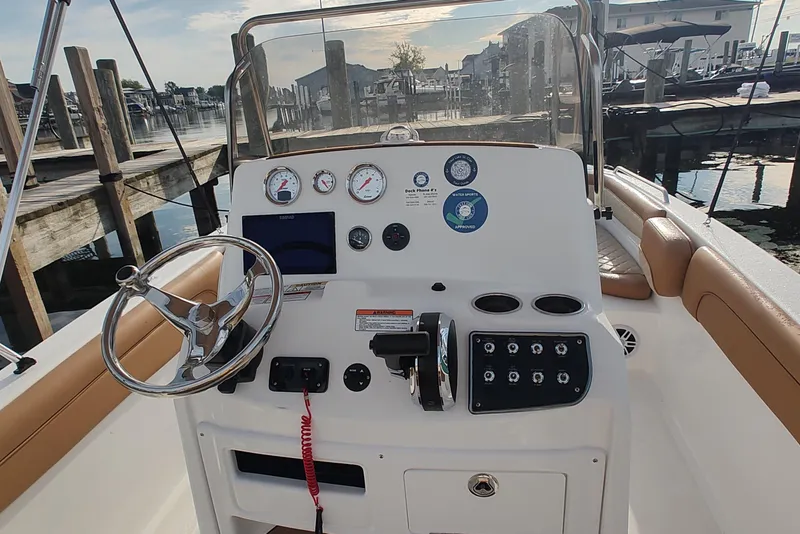 Slide: The Image of 2026 NauticStar 231 Hybrid boat dashboard with steering wheel and control panel at marina. - 12