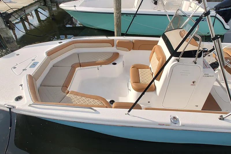 Slide: The Image of 2026 NauticStar 231 Hybrid boat with tan seating, docked in marina. - 3