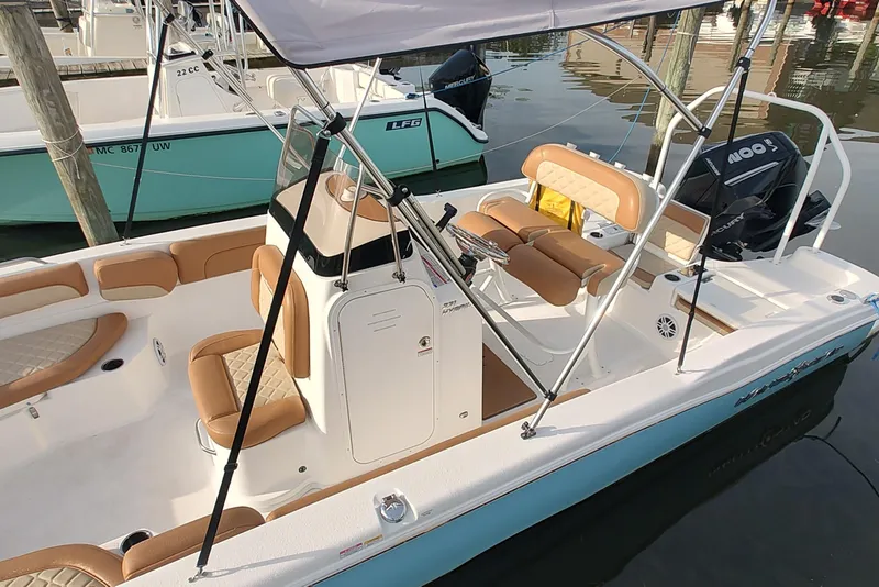 Slide: The Image of 2026 NauticStar 231 Hybrid boat with tan seating and canopy docked in marina. - 4