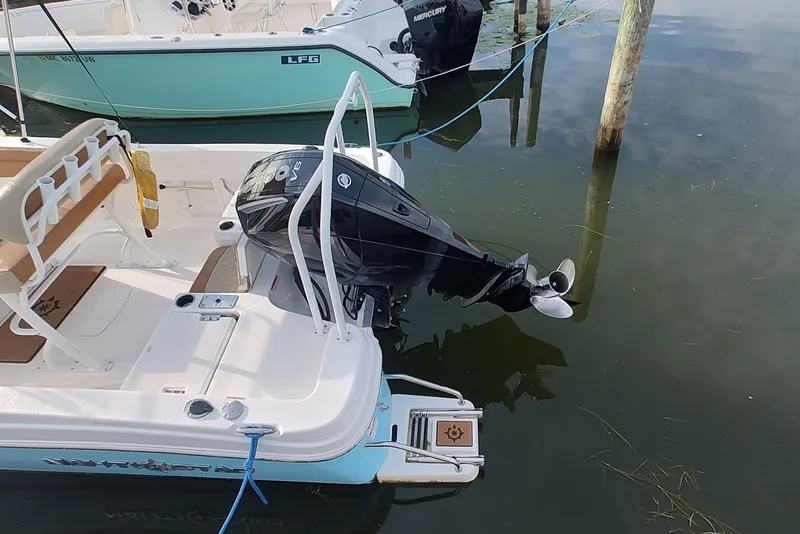 Slide: The Image of 2026 NauticStar 231 Hybrid boat with Mercury outboard motor docked in calm water. - 6