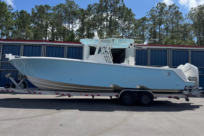 The Image of 2024 SeaVee 32Z boat on trailer, parked outdoors with trees in background. - 0