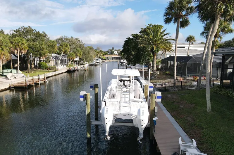 Slide: The Image of 2023 Twin Vee 260 GFX boat docked in a scenic canal with palm trees. - 2