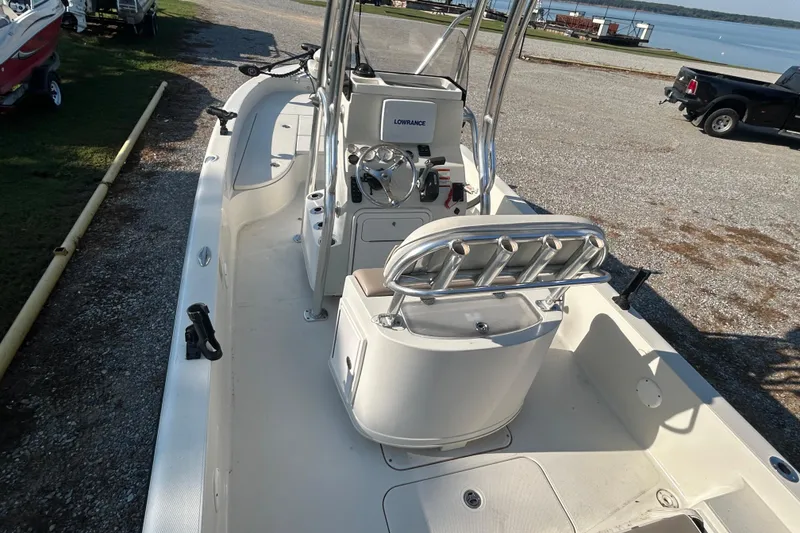 Slide: The Image of 2009 Ranger 2410 Bay Ranger boat with steering console and rod holders, docked near a lake. - 10