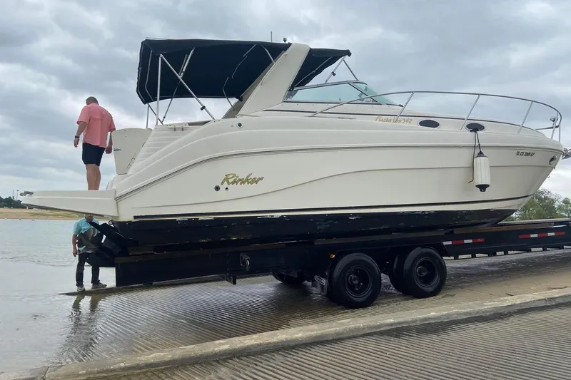 Slide: The Image of 2003 Rinker 342 Express Cruiser on trailer in a calm lake setting. - 12
