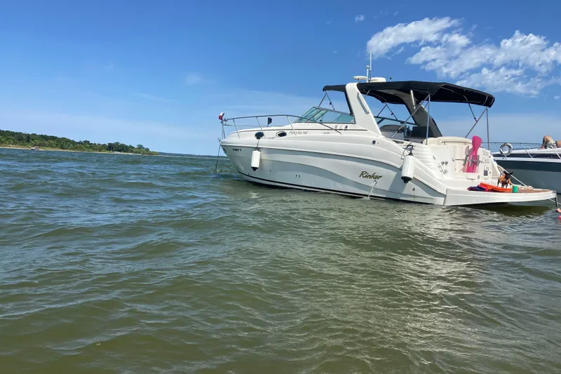 Slide: The Image of 2003 Rinker 342 Express Cruiser on trailer, transported by a semi-truck in a parking lot. - 14