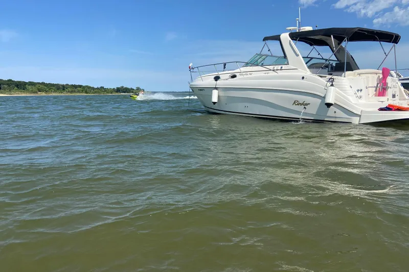 Slide: The Image of 2003 Rinker 342 Express Cruiser anchored on a sunny day in open water. - 15