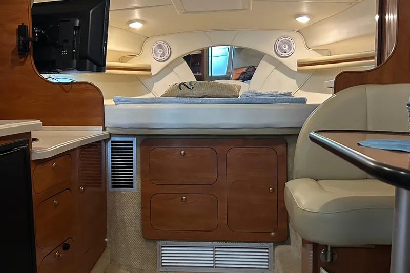 Slide: The Image of 2003 Rinker 342 Express Cruiser cabin interior with bed, TV, and wooden cabinetry. - 22