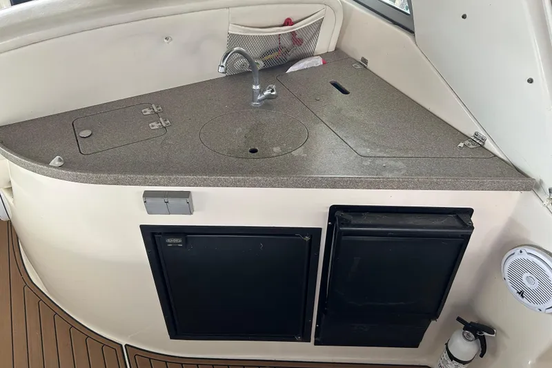Slide: The Image of 2003 Rinker 342 Express Cruiser kitchenette with sink, storage, and appliances. - 26