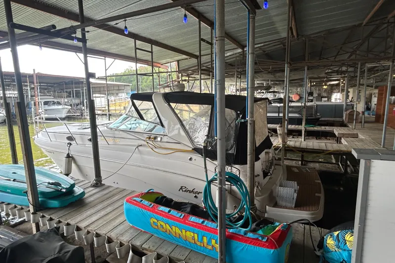 Slide: The Image of 2003 Rinker 342 Express Cruiser docked in a covered marina with water sports equipment. - 27