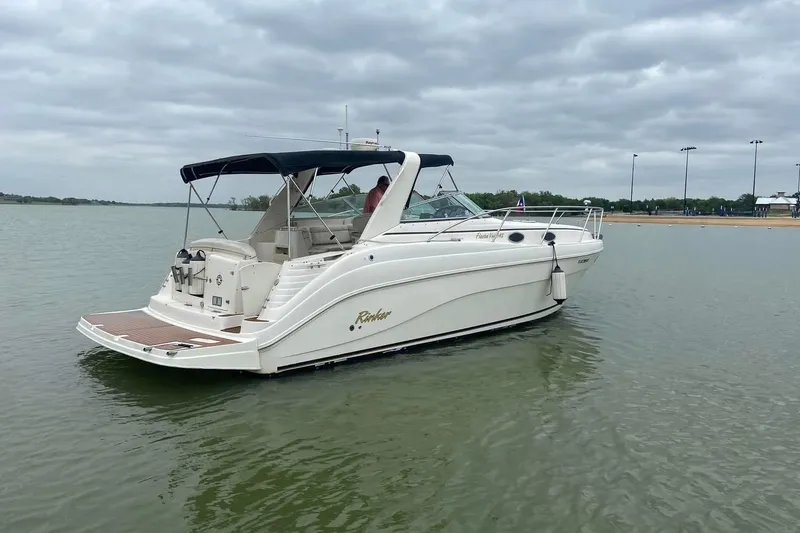Slide: The Image of 2003 Rinker 342 Express Cruiser on calm water near a bridge. - 6