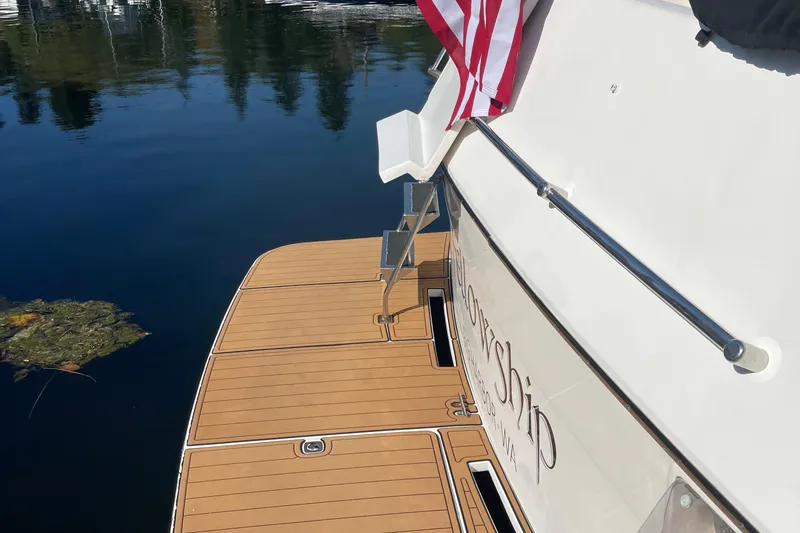 Slide: The Image of 1997 McKinna 48 Pilothouse yacht with American flag, docked on calm water. - 12