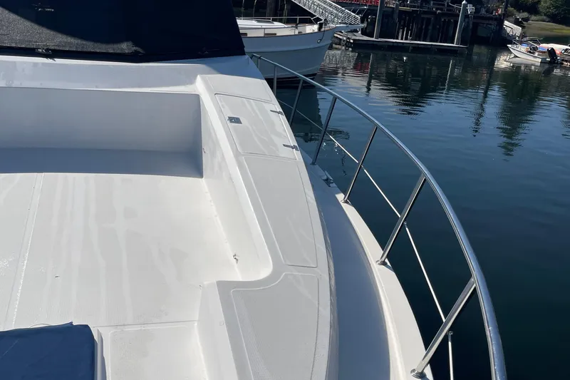 Slide: The Image of 1997 McKinna 48 Pilothouse yacht deck with railing, docked by calm water. - 21