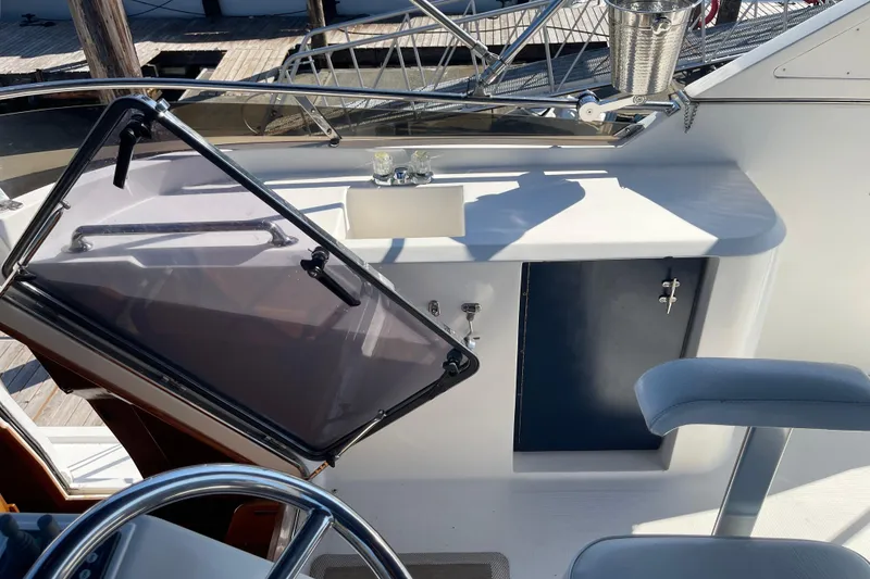 Slide: The Image of 1997 McKinna 48 Pilothouse helm station with steering wheel, controls, and storage compartment. - 47