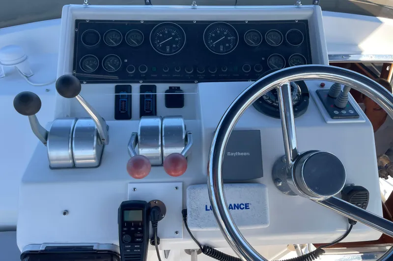 Slide: The Image of Control panel of a 1997 McKinna 48 Pilothouse yacht with steering wheel and gauges. - 48