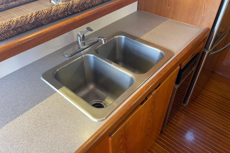 Slide: The Image of Kitchen sink area in 1997 McKinna 48 Pilothouse yacht with wooden cabinetry. - 70