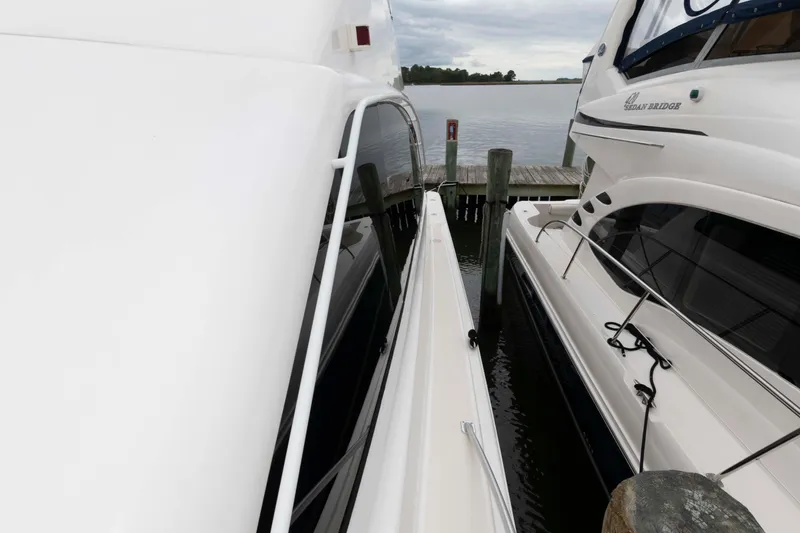 Slide: The Image of 2004 Ocean Yachts 52 SUPER SPORT docked beside another yacht on a calm waterway. - 16