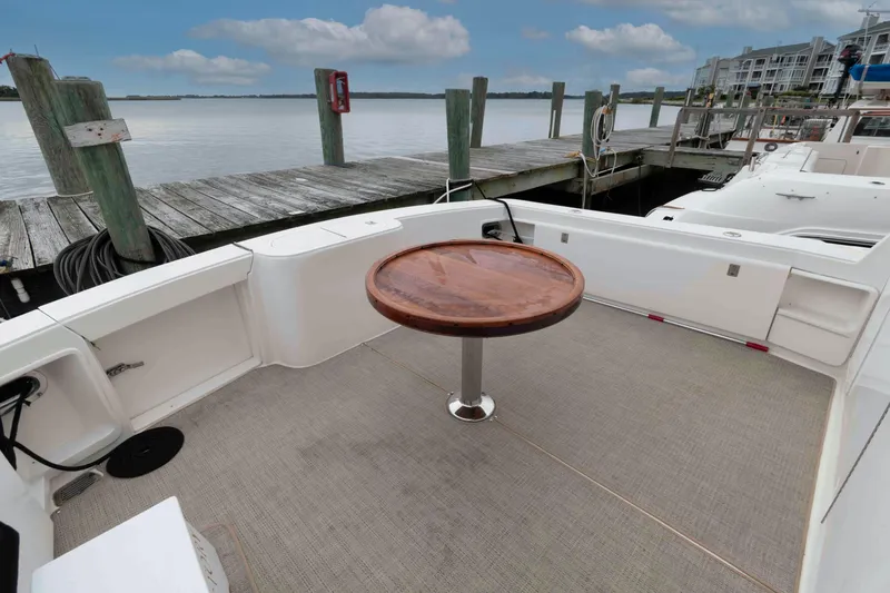 Slide: The Image of 2004 Ocean Yachts 52 SUPER SPORT deck with wooden table, docked by the water. - 4