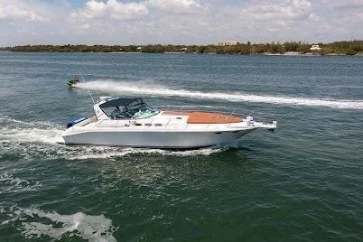 Slide: The Image of 1997 Sea Ray 400 Express Cruiser navigating a scenic waterway under a partly cloudy sky. - 10