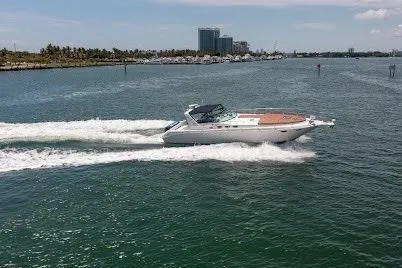 Slide: The Image of 1997 Sea Ray 400 Express Cruiser speeding on open water near coastline. - 15