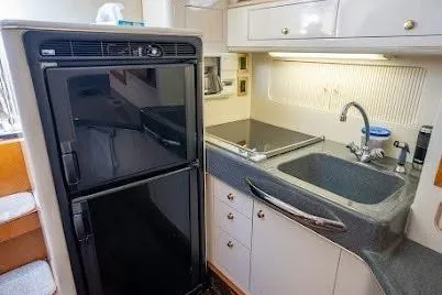 Slide: The Image of 1997 Sea Ray 400 Express Cruiser kitchen with fridge, sink, and stove. - 18