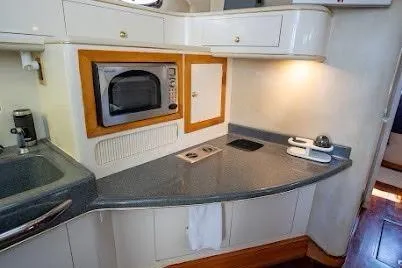 Slide: The Image of 1997 Sea Ray 400 Express Cruiser kitchen with microwave, sink, and countertop. - 19